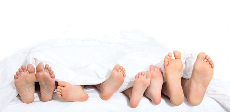 Pieds d'une famille, dans un lit blanc