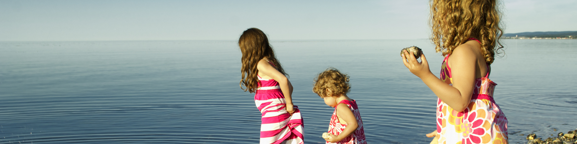 3 petites filles jouant sur la page, près de l'eau