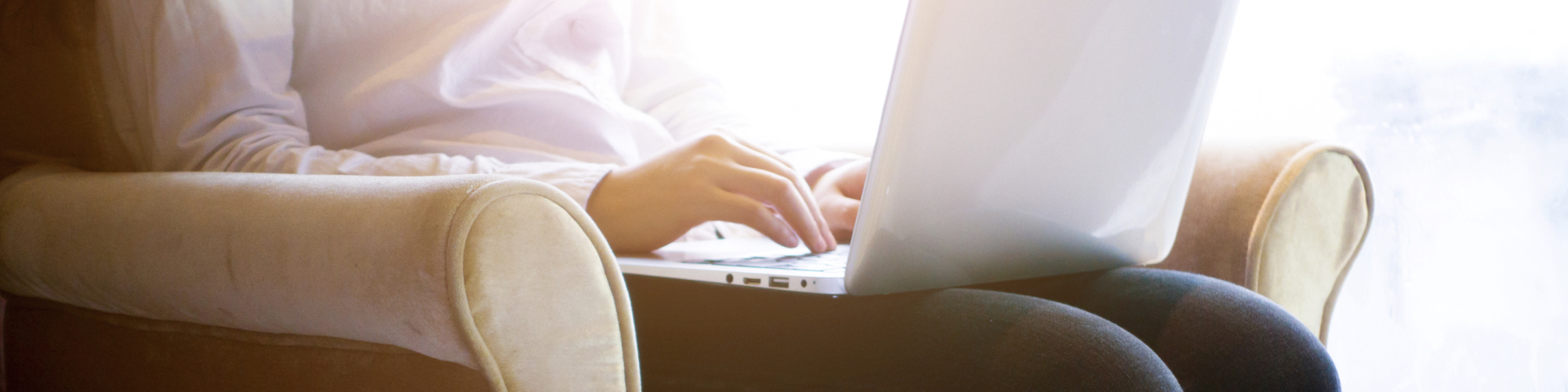 Woman, sitting in an armchair, with a laptop