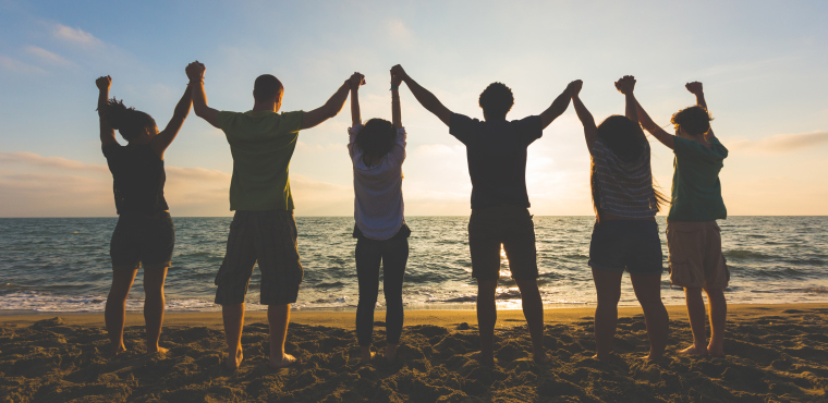 Groupe de personnes main dans la main sur la plage