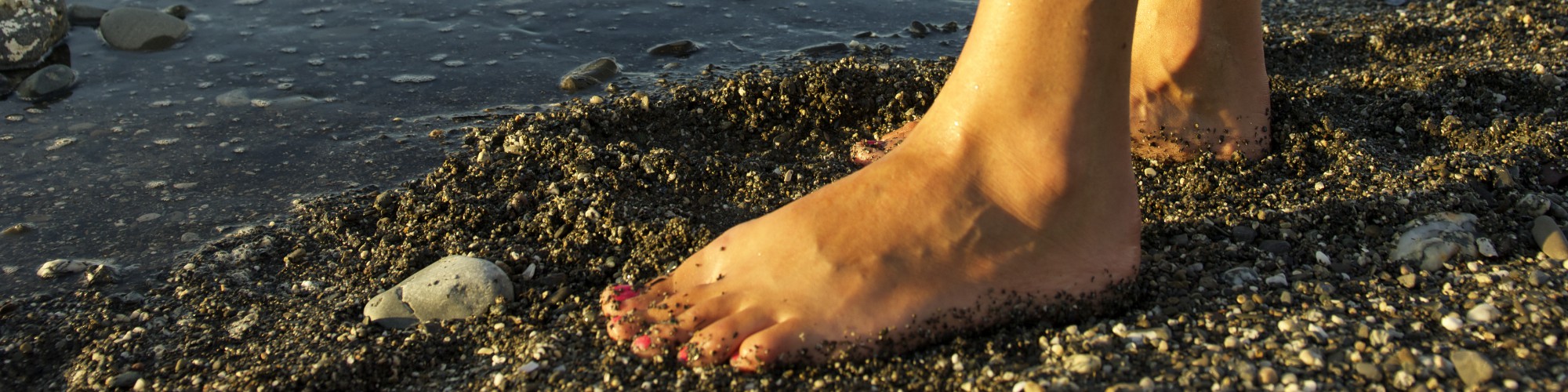 Bare feet on the beach, young boy sea kayaking