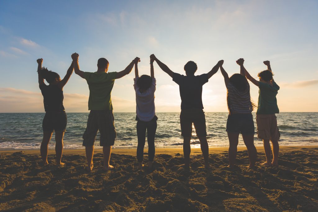 Groupe de personnes main dans la main sur la plage
